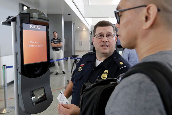 CBP officer helping traveler get scanned